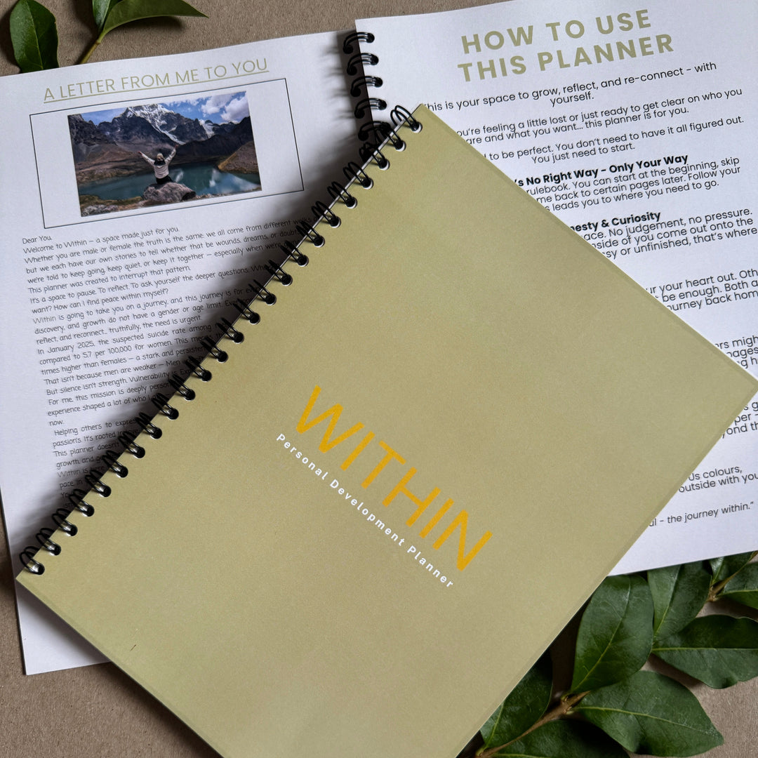 Spiral-bound notebook with 'WITHIN' branding on a surface with text and leaves.