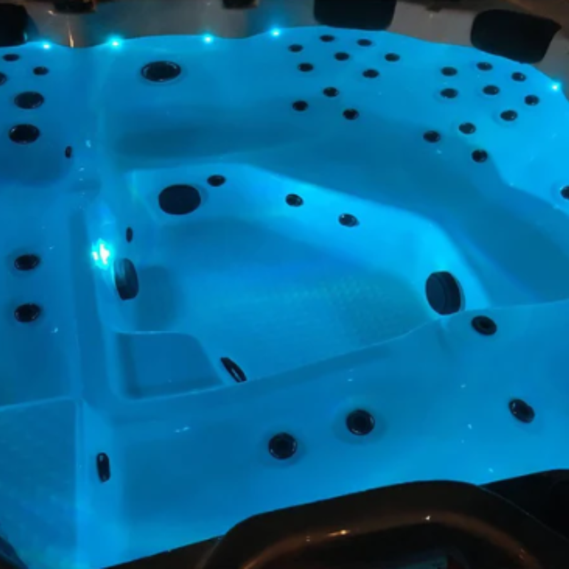 An upclose shot of the Vancouver 65-Jet 6-Person Hot Tub that has been filled with wtaer. Because the jets are not on you can see the jets through the still water. 